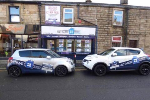 two company cars parked nose to nose outside the Ultimate Property Solutions office